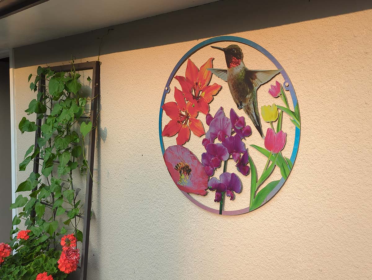 The final artwork hanging on the garage wall, between two potted flowers